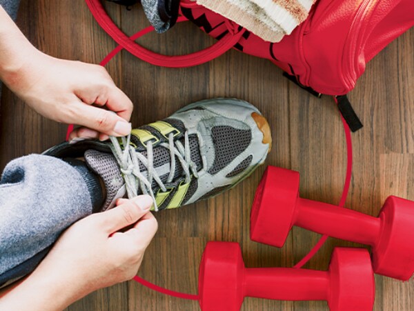 Person bindet die Sportschuhe im GYM Fitnessstudio - Fußpilz behandeln mit Canesten® EXTRA