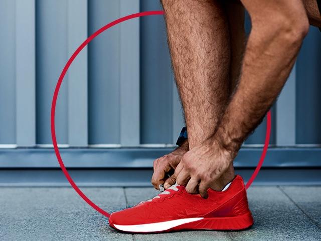 Mann bindet sich die Sportschuhe - Fußpilz behandeln mit Canesten® EXTRA