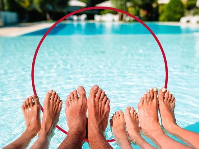 Familie hält ihre Füße ins Wasser - Fußpilz behandeln mit Canesten® EXTRA
