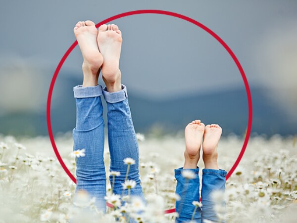 Frau und Kind liegen im Gras - Nagelpilz behandeln mit Canesten® EXTRA