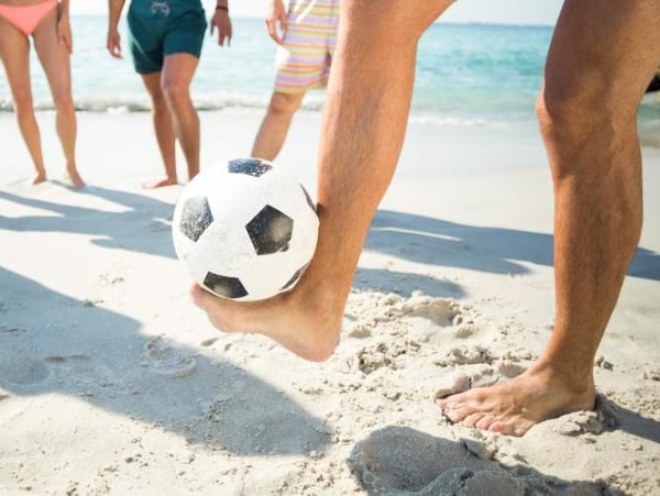 Fussballer haelt Ball mit dem Fuss – Fusspflege bei sportlicher Aktivitaet.