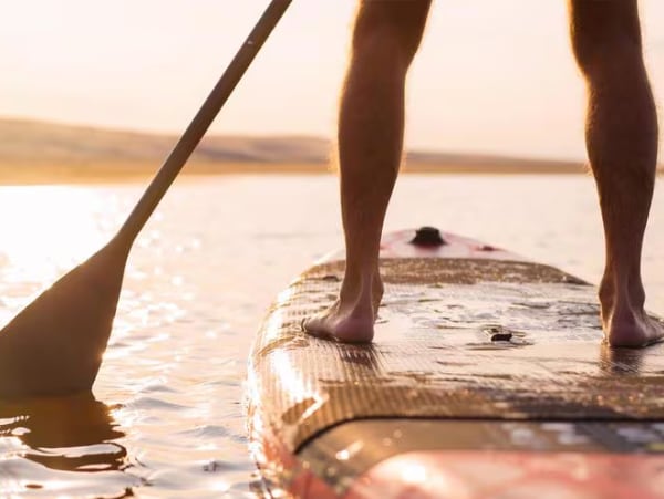 Stand-up-Paddler bei Sonnenuntergang – Fussgesundheit und Balance.